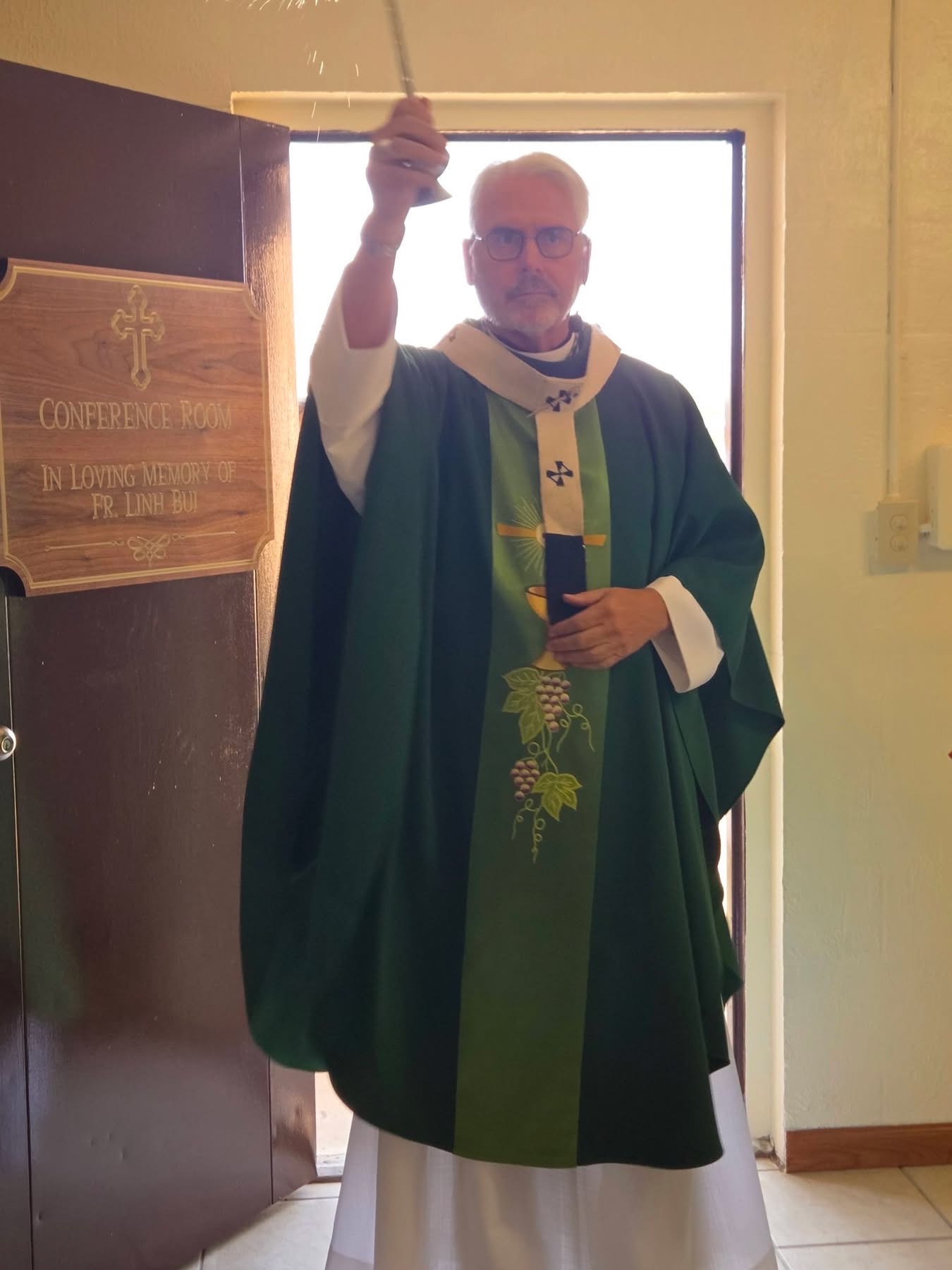 Archbishop Coakley blessing the new Conference and Media Room beside its dedication plaque